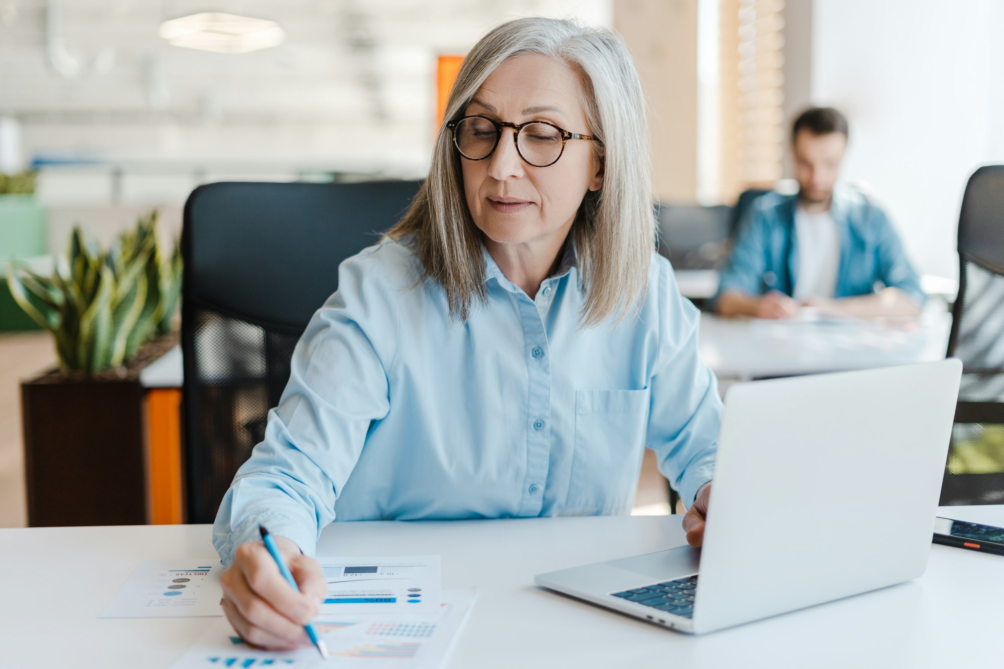 Caucasian mature business woman, making notes, sitting at desk with laptop. Business. People. Career