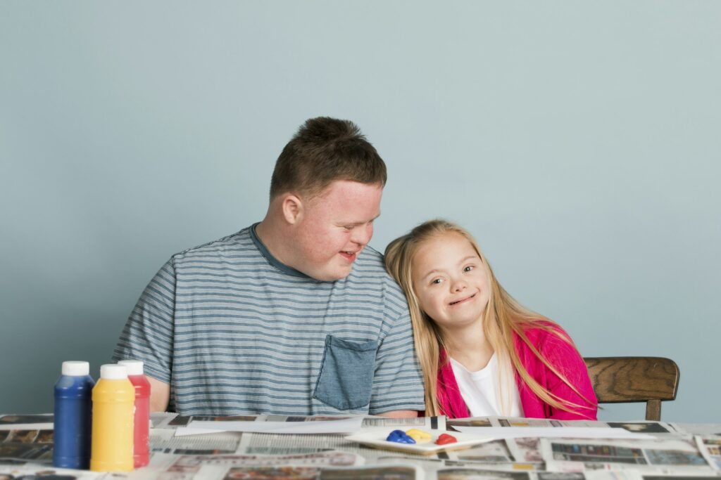 Cute siblings with down syndrome playing with paint