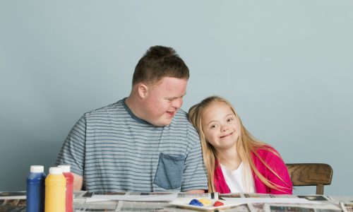 Cute siblings with down syndrome playing with paint